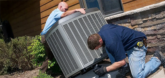 Technicians replacing a new outdoor air conditioning unit beside a home